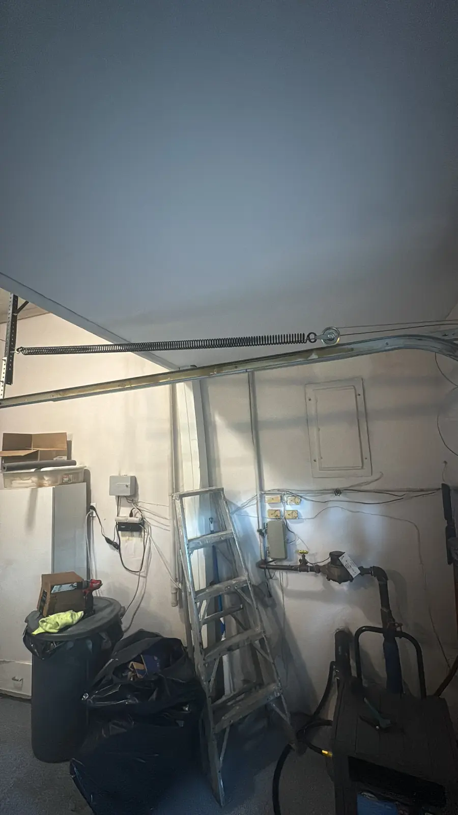 Overhead garage door extension spring along side track at service site